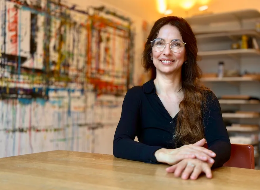 Andrea Fritz, Inhaberin der Praxis sinn.bild, an einem Tisch vor einem großformatigen abstrakten Bild