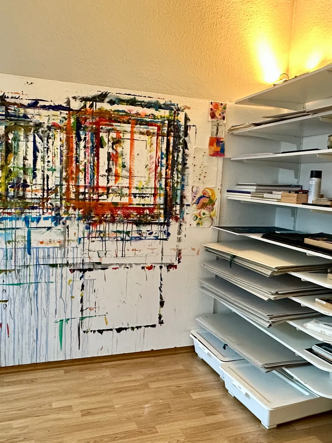Ein großformatiges abstraktes Bild an der Wand, daneben ein Planschrank mit flachen Fächern
